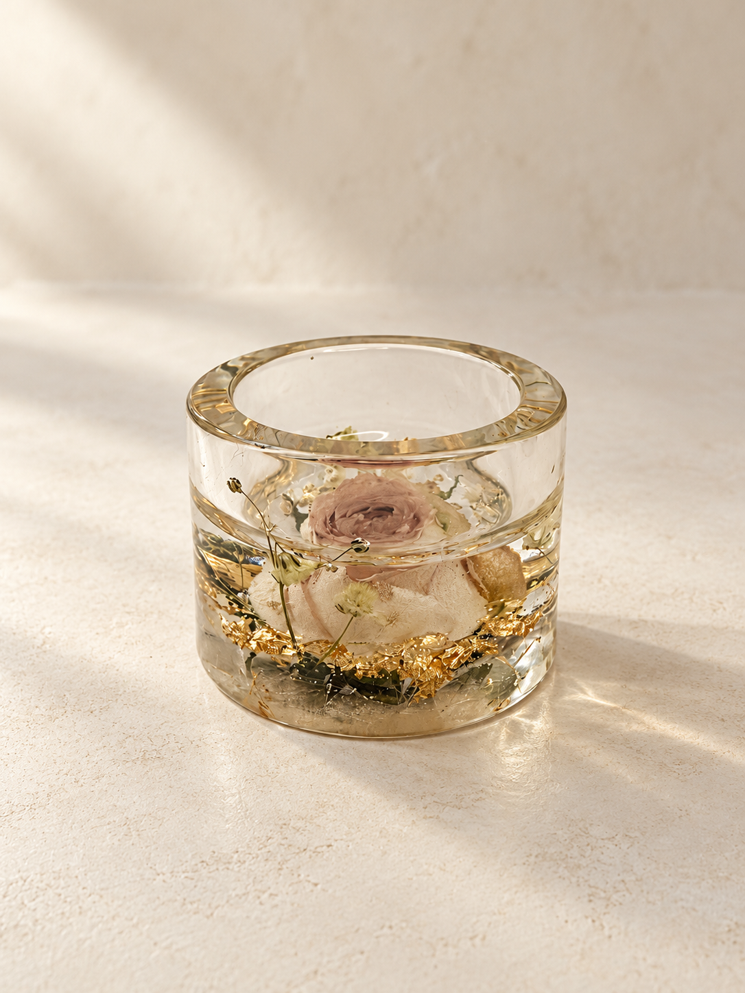 Angled view of a clear resin candle holder with a real blush rose and gold-coloured flakes, handmade in Lancashire UK by Held Forever Studio