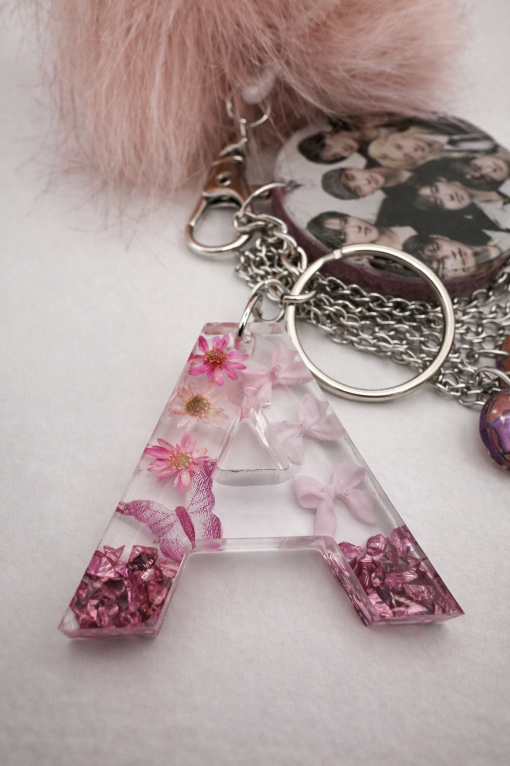 Close up of personalised K-pop keychain bundle with resin photo charms and faux fur pom pom