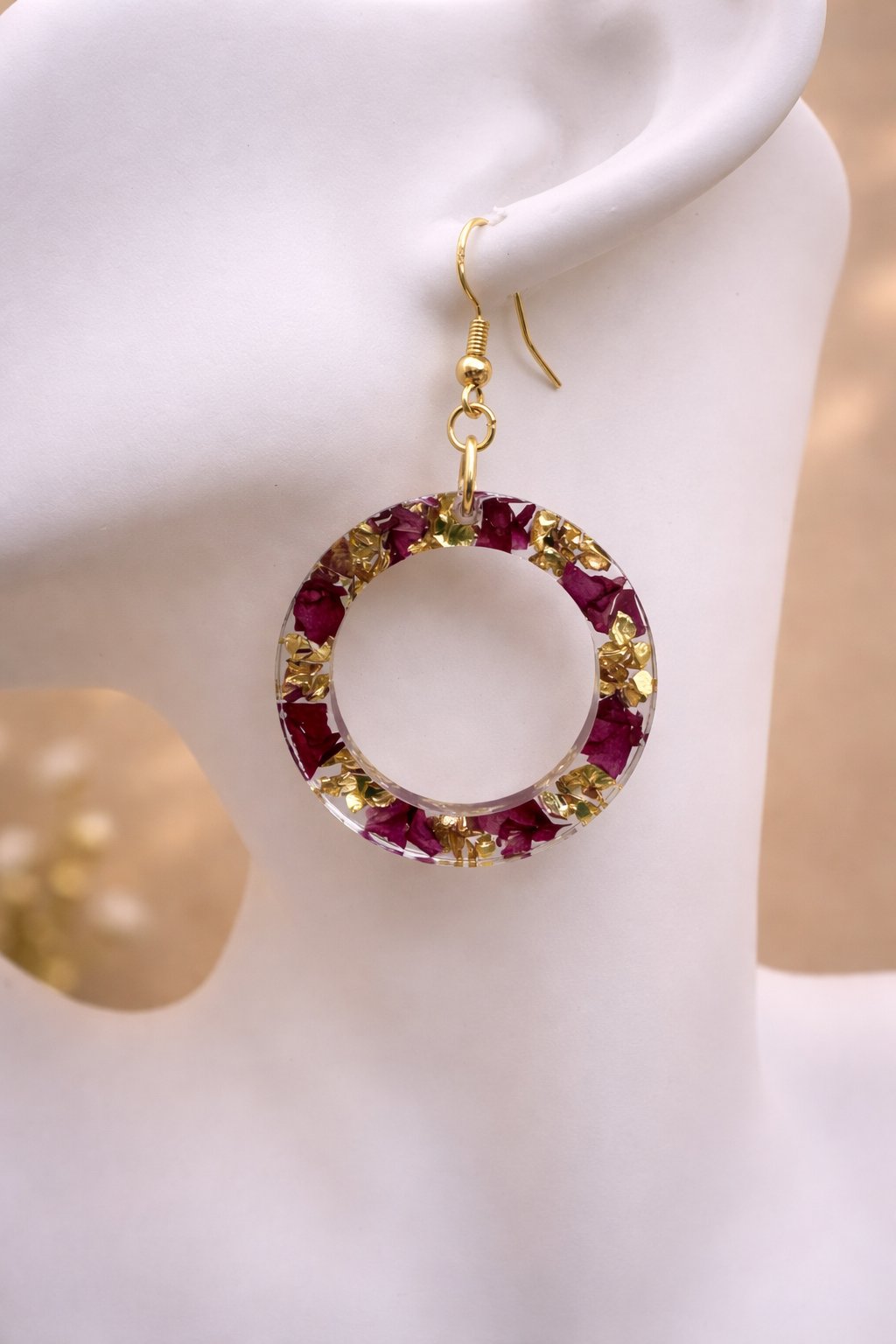 Close up of resin hoop earring showing real dried flowers and gold foil inclusions, handmade in Lancashire UK by Held Forever Studio