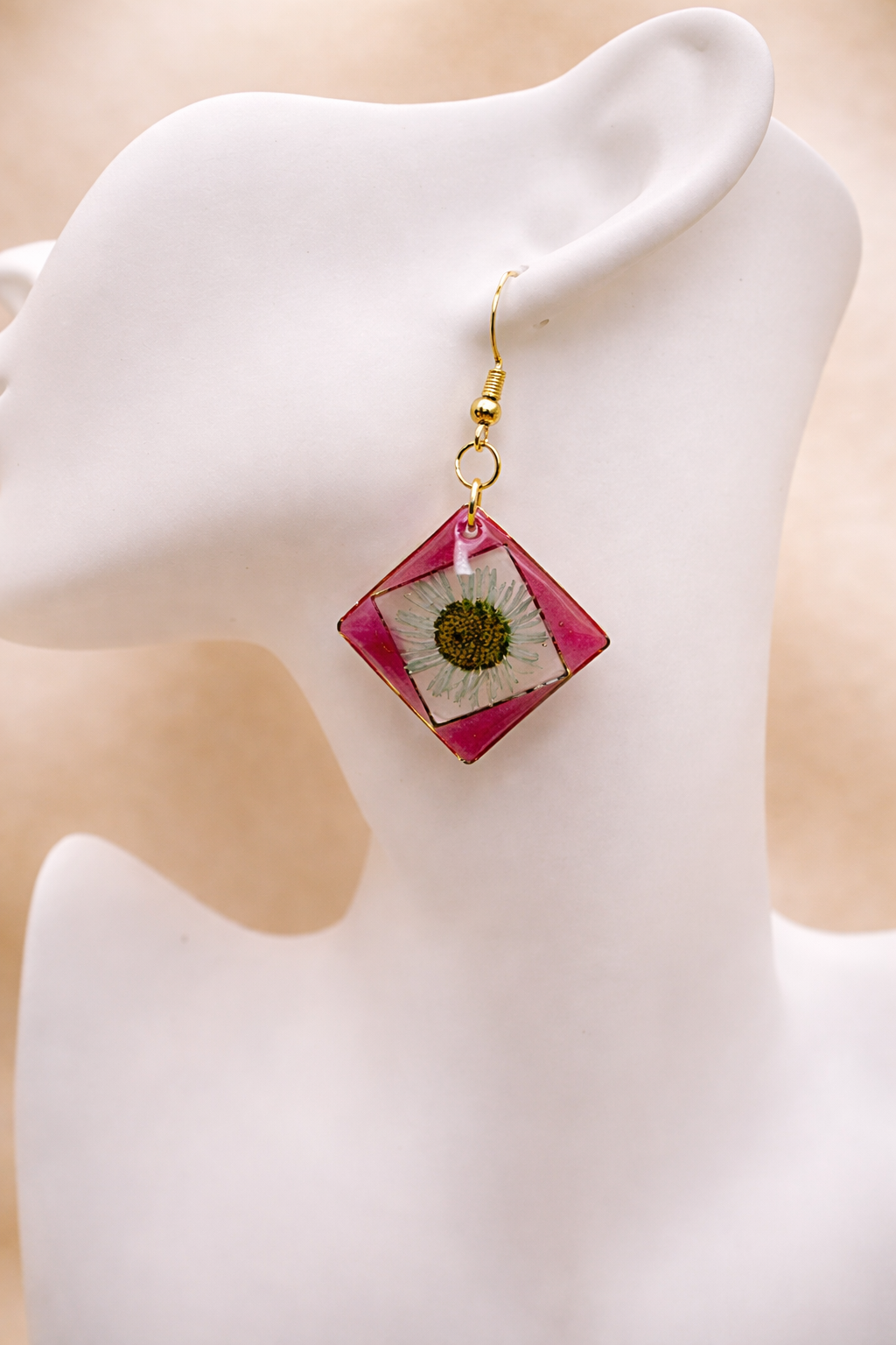 Pair of pink resin diamond drop earrings with real pressed daisy on mannequin display, handmade by Held Forever Studio
