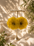 Pair of yellow pressed flower resin disc earrings with 925 sterling silver hooks on a stand, handmade by Held Forever Studio