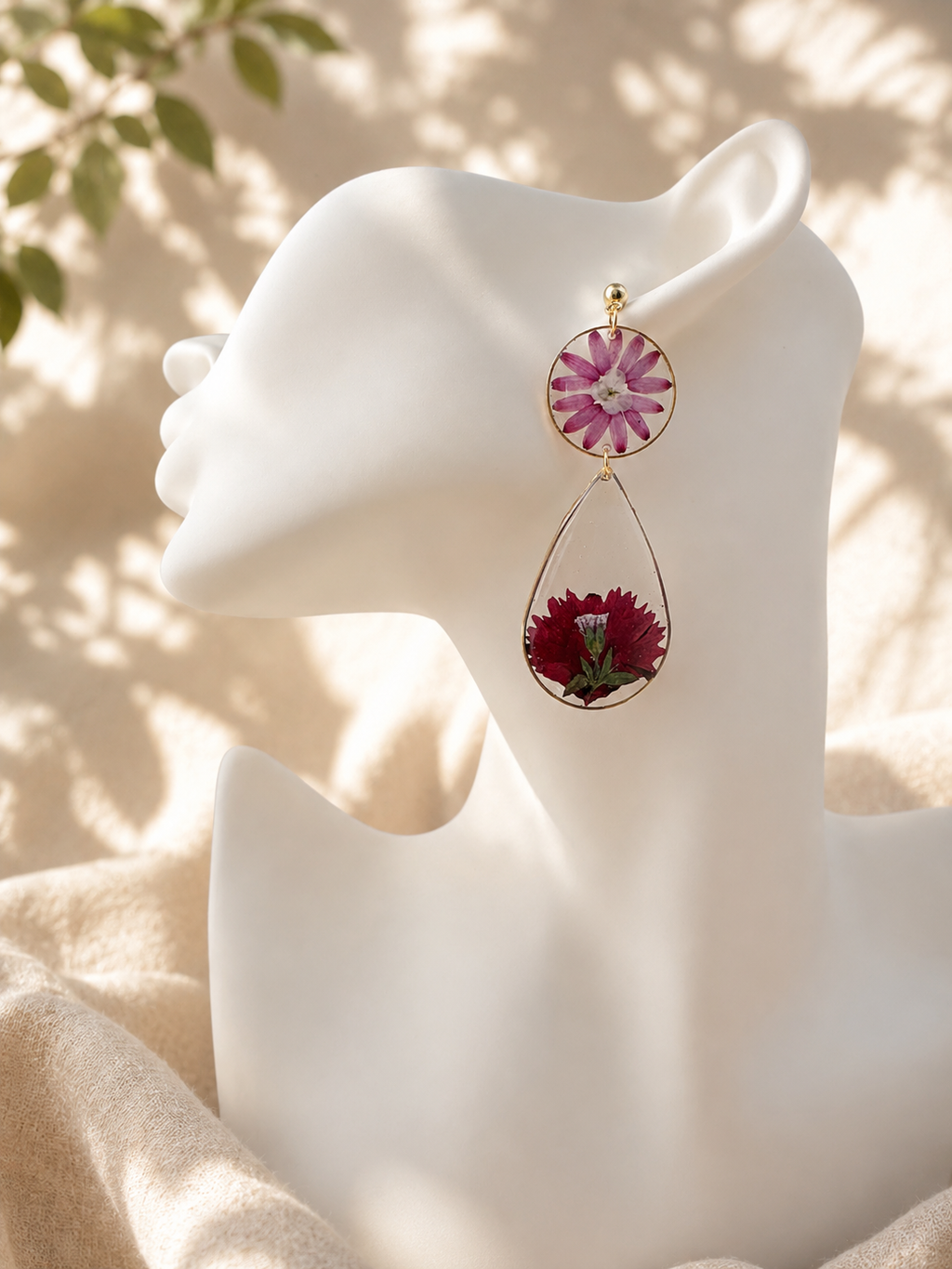 Pair of pressed flower resin drop earrings on a stand showing pink and burgundy pressed flowers, handmade in Lancashire UK