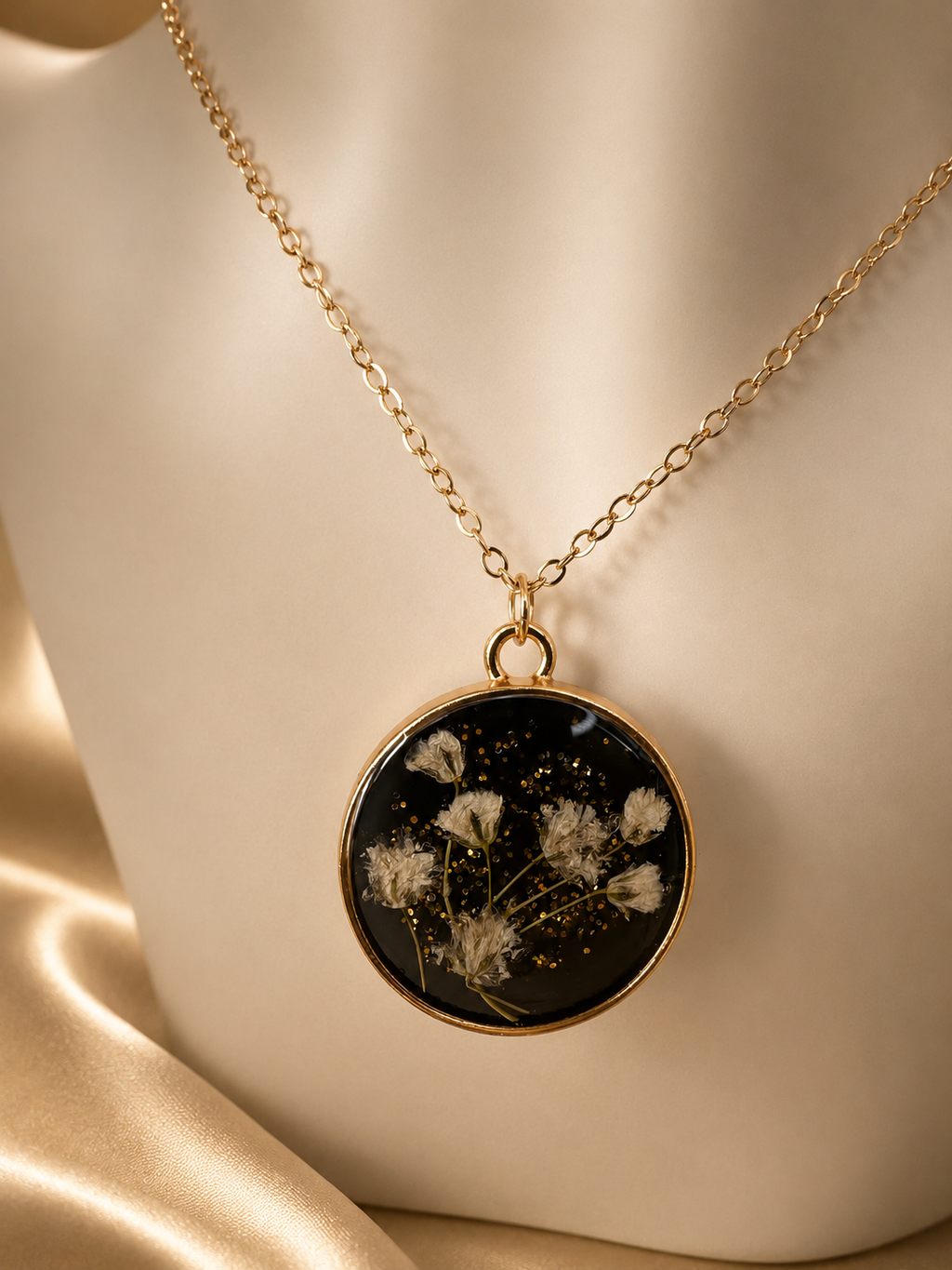 Black resin pendant necklace with real dried flowers and gold glitter on gold satin, handmade by Held Forever Studio in Lancashire UK