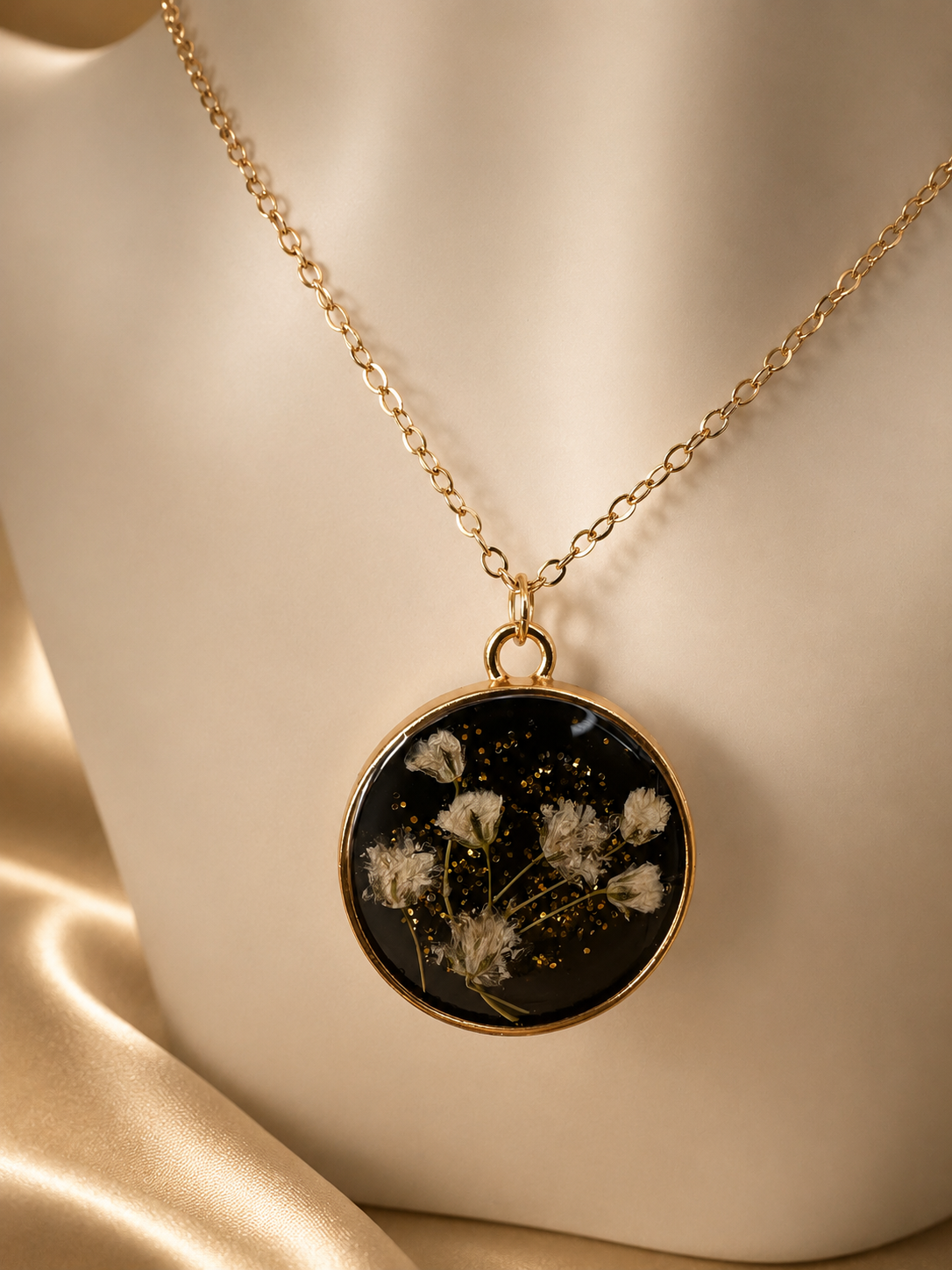 Black resin pendant necklace with real dried flowers and gold glitter on gold satin, handmade by Held Forever Studio in Lancashire UK