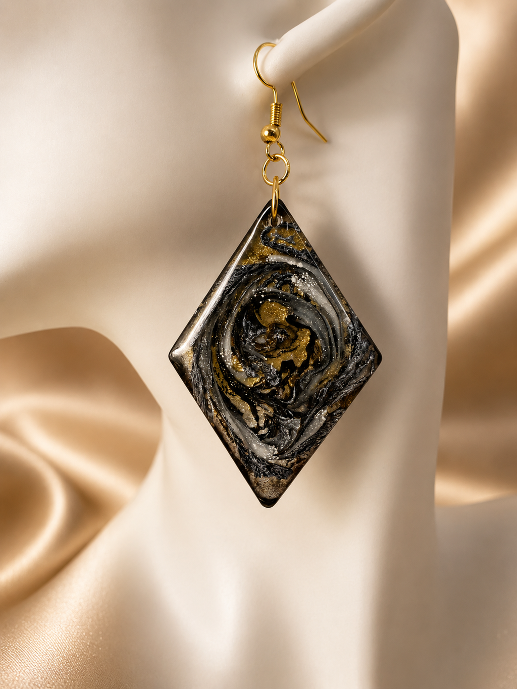 Close up of black, gold and silver marble diamond resin drop earring showing swirl detail, handmade in Lancashire UK