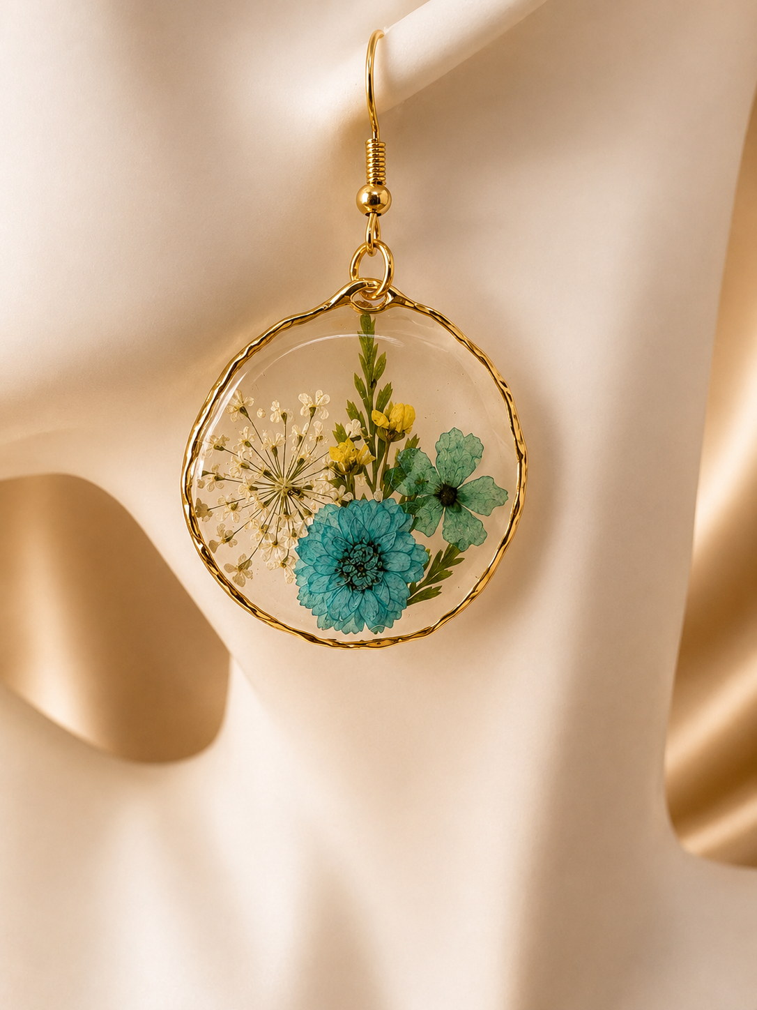 Pair of real pressed flower resin drop earrings with polished gold wire frame on jewellery display, handmade in Lancashire UK by Held Forever Studio