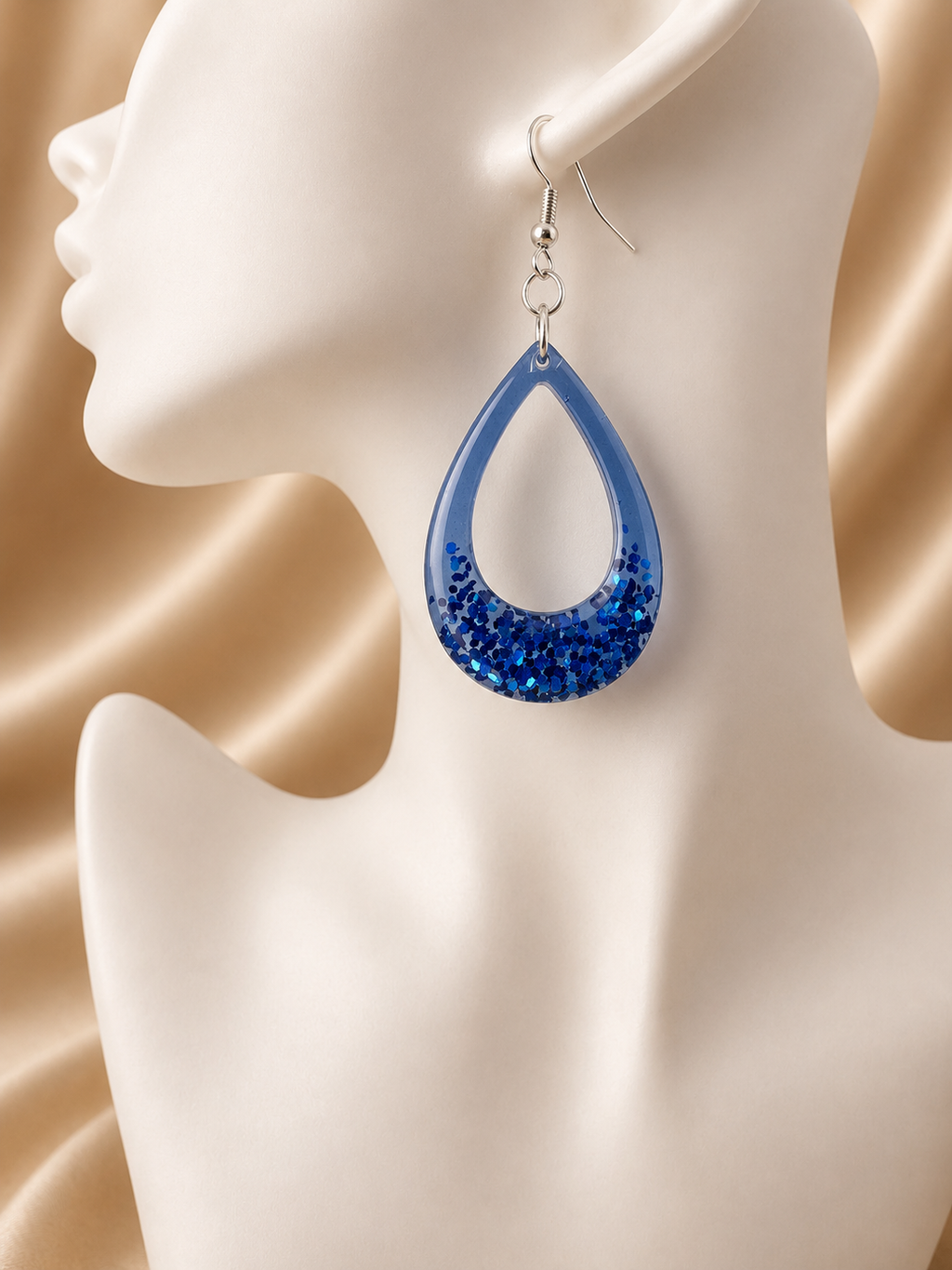 Blue glitter resin teardrop hoop earrings pair on jewellery display, handmade in Lancashire UK by Held Forever Studio