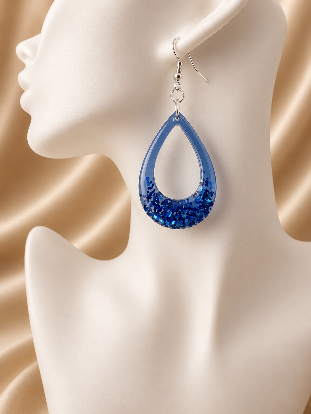 Blue glitter resin teardrop hoop earrings pair on jewellery display, handmade in Lancashire UK by Held Forever Studio