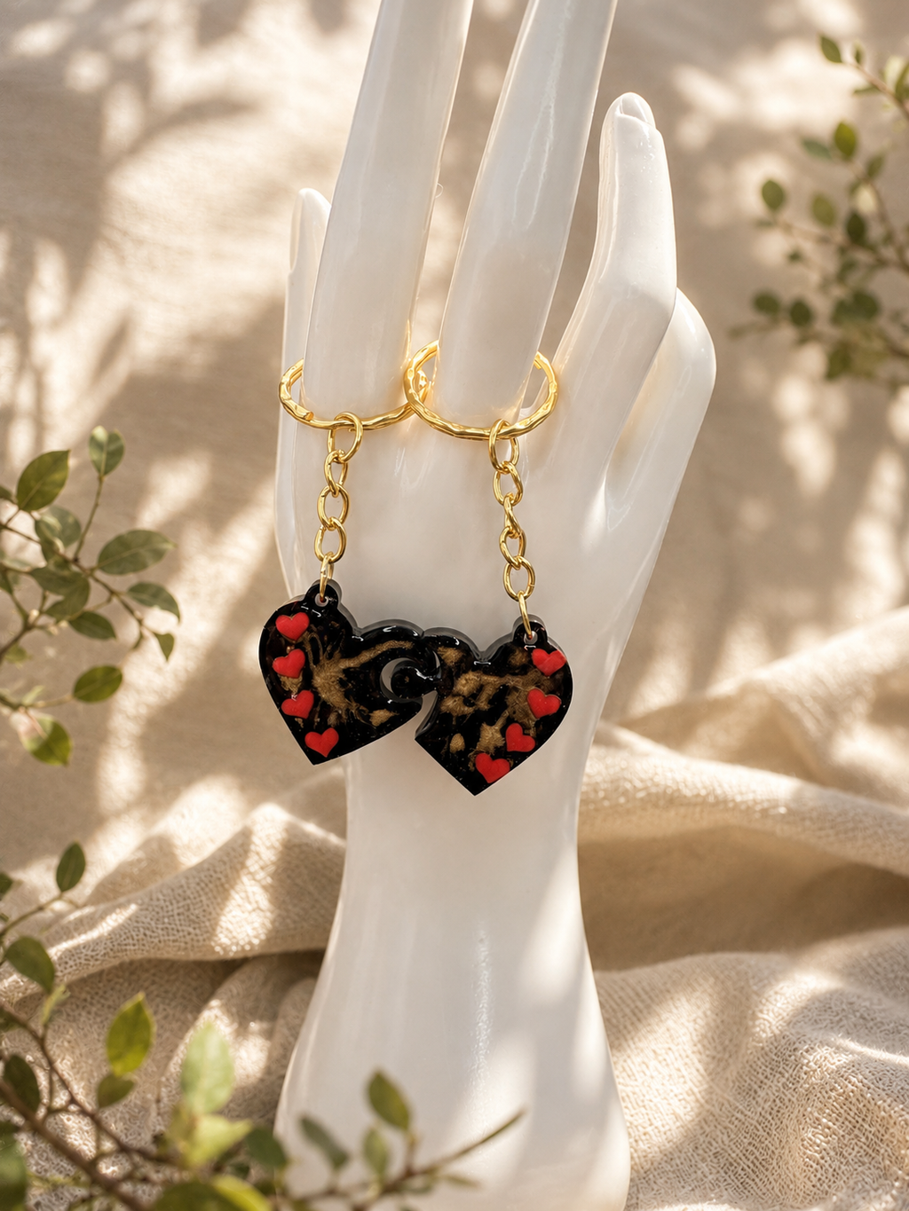 Interlocking resin heart keyrings separated to show puzzle design, black with gold marble swirl, handmade by Held Forever Studio