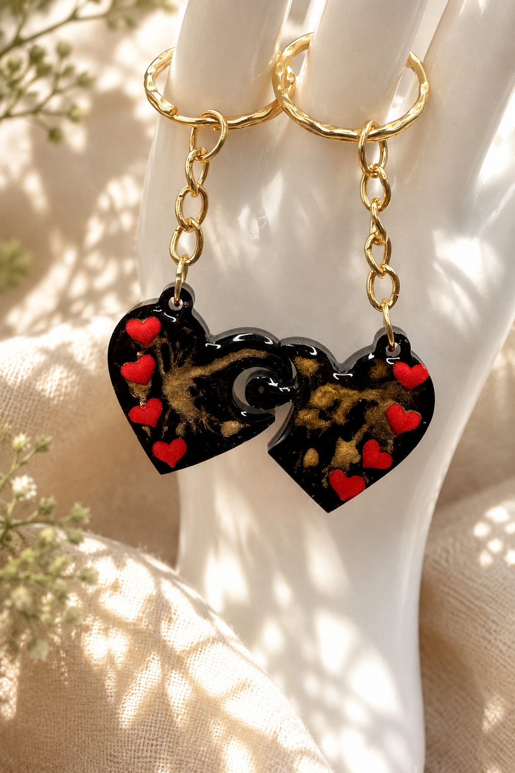 Two matching heart resin keyrings hanging on ceramic hand display showing gold chain hardware, handmade in Lancashire UK