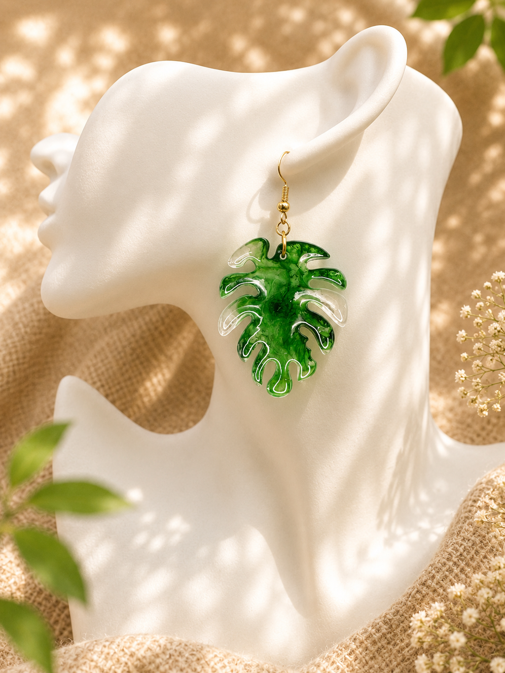 Close up of green marble resin monstera leaf drop earring on ceramic bust display, handmade in Lancashire UK by Held Forever Studio