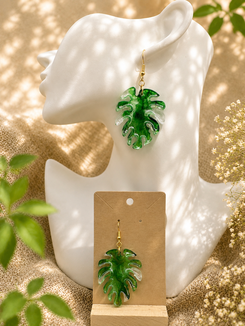Green and white marble resin monstera leaf drop earrings on styled display stand with earring card, handmade by Held Forever Studio