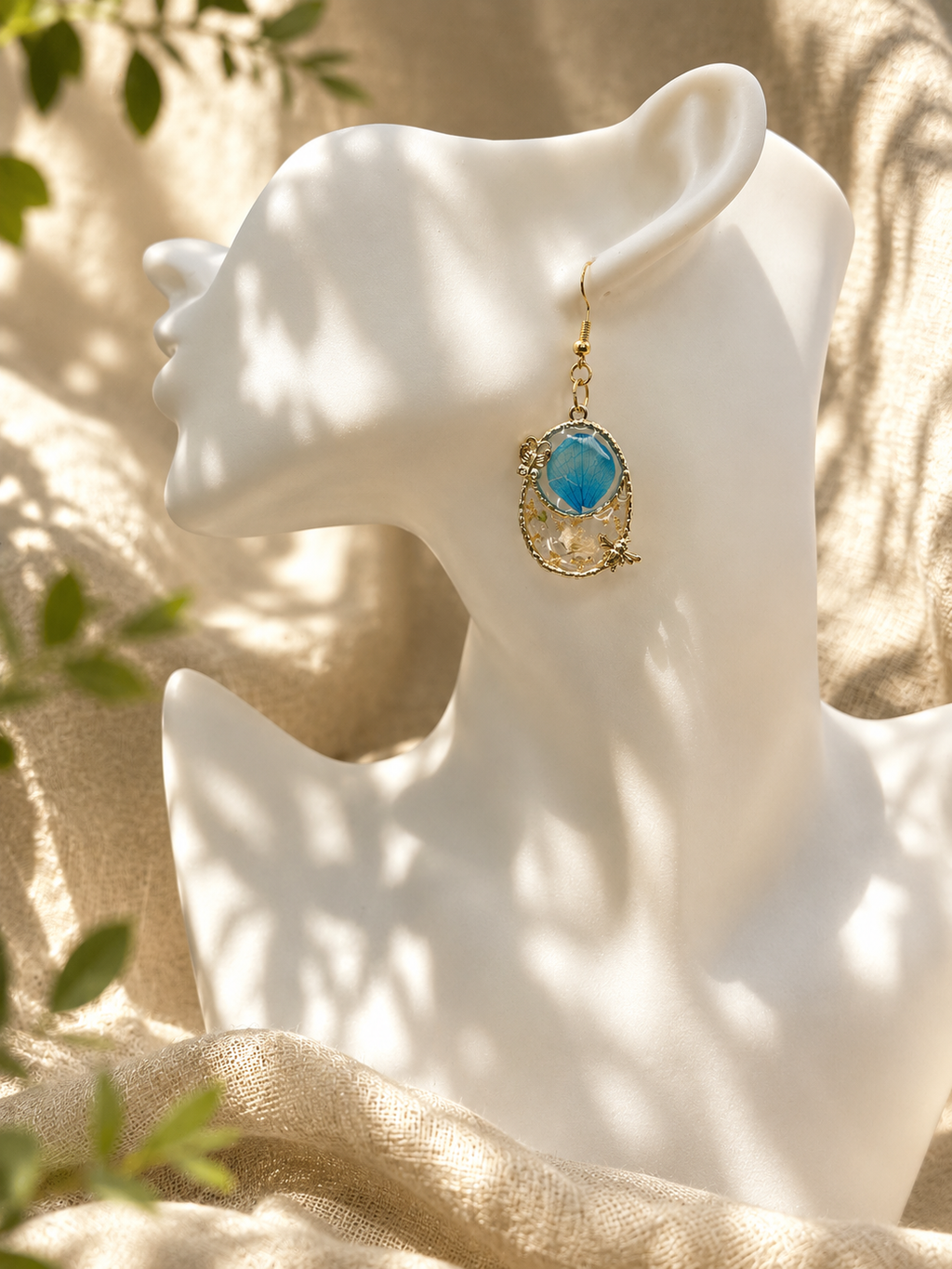 Pair of resin drop earrings in gold filigree frames with botanical inclusions shown on white bust and black earring card — handmade in Lancashire UK by Held Forever Studio