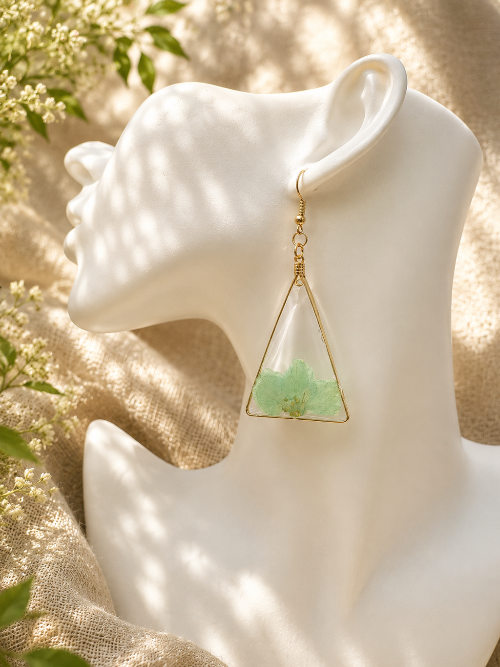 Close up of pressed green flower triangle resin drop earring worn on mannequin ear, handmade in Lancashire UK by Held Forever Studio