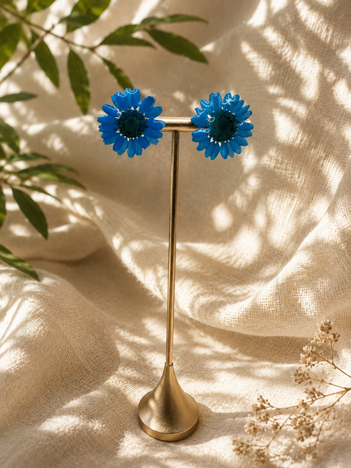 Blue daisy resin stud earrings with 24k gold-plated studs, close up on display stand, handmade by Held Forever Studio