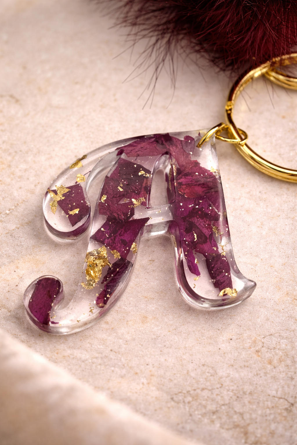 Close up of personalised resin letter keyring with dried flower petals and gold leaf flakes by Held Forever Studio