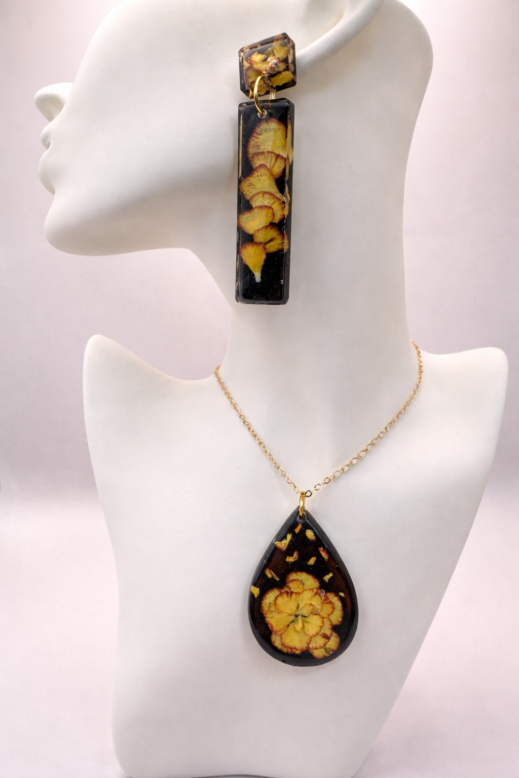 Black UV resin teardrop pendant necklace with real pressed pansy and gold leaf on gold-plated stainless steel chain, handmade in Lancashire UK