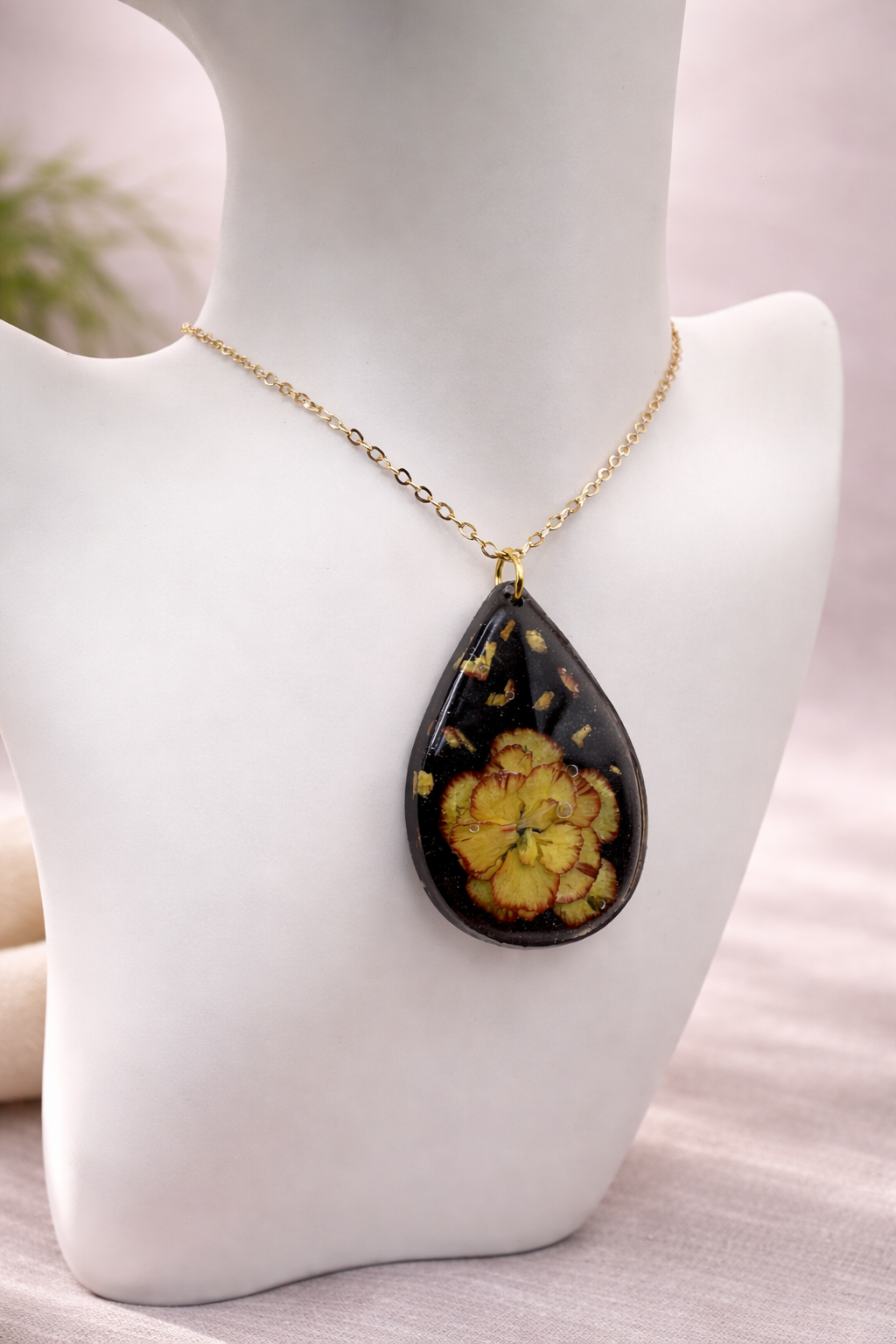 Close-up of black UV resin rectangular bar earring with cascading real pressed pansies and gold leaf flakes, handmade by Held Forever Studio