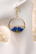 Pressed blue cornflower resin drop earring with gold leaf in a gold-toned open-circle frame, handmade by Held Forever Studio