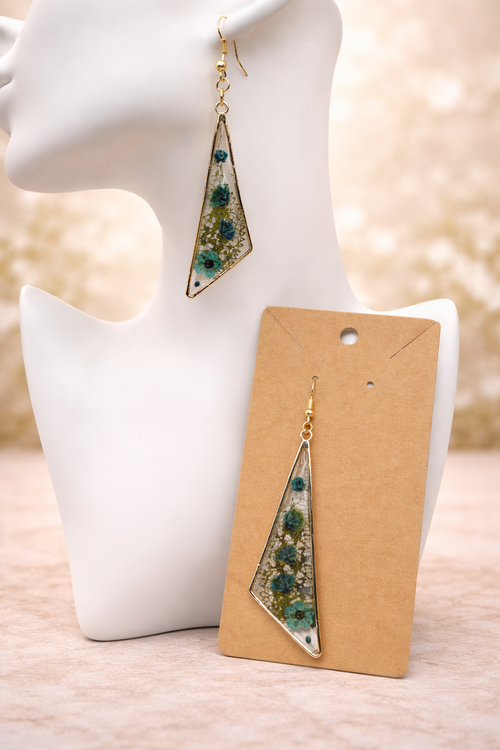 Close up of blue pressed flower resin drop earring showing real pressed forget-me-nots, cornflower and white gypsophila in clear resin, handmade by Held Forever Studio