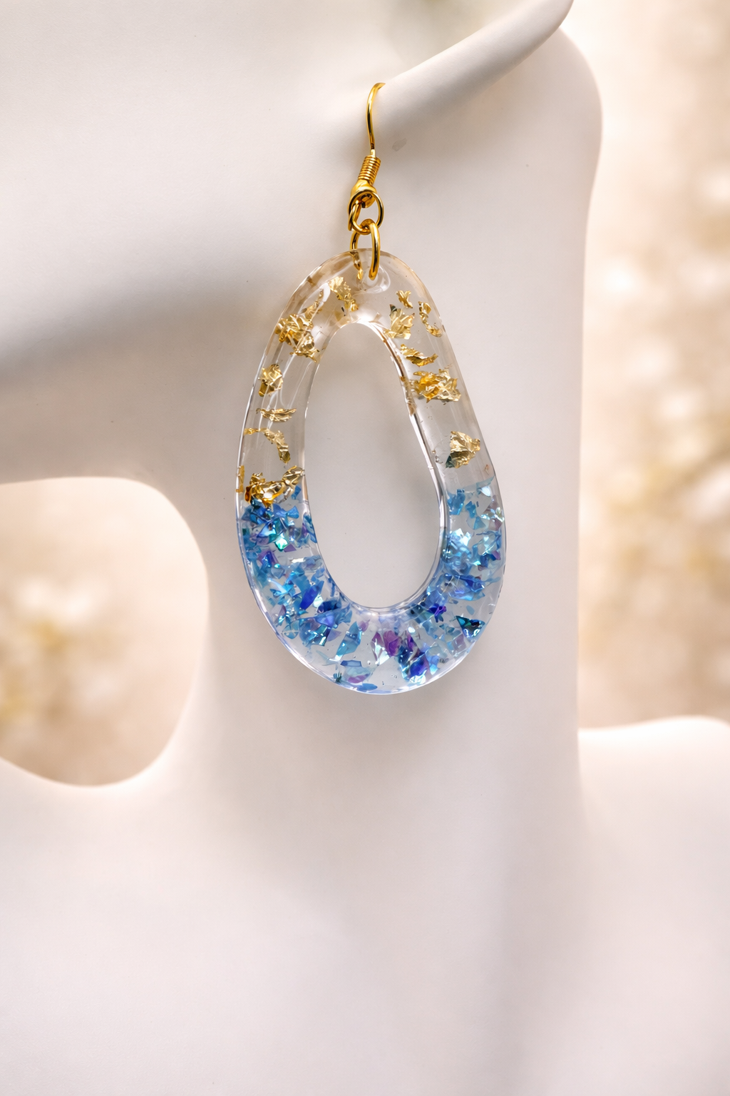 Blue iridescent resin teardrop drop earrings with gold leaf flakes on display card, handmade by Held Forever Studio