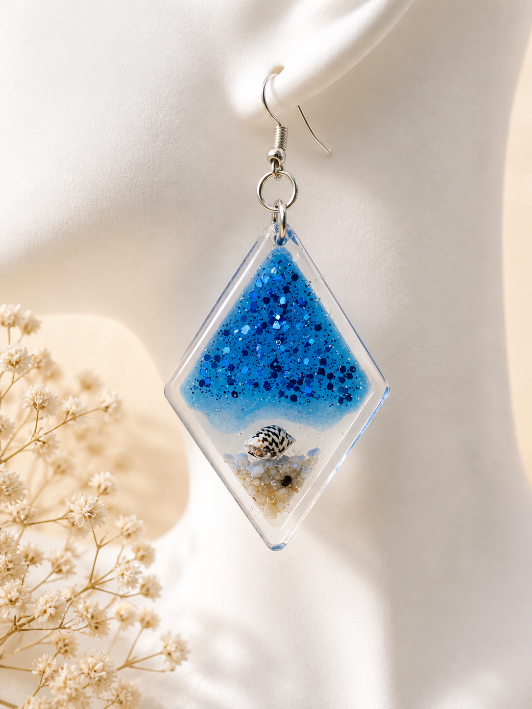 Flat lay of ocean diamond resin drop earrings showing both earrings with beach scene detail, handmade by Held Forever Studio