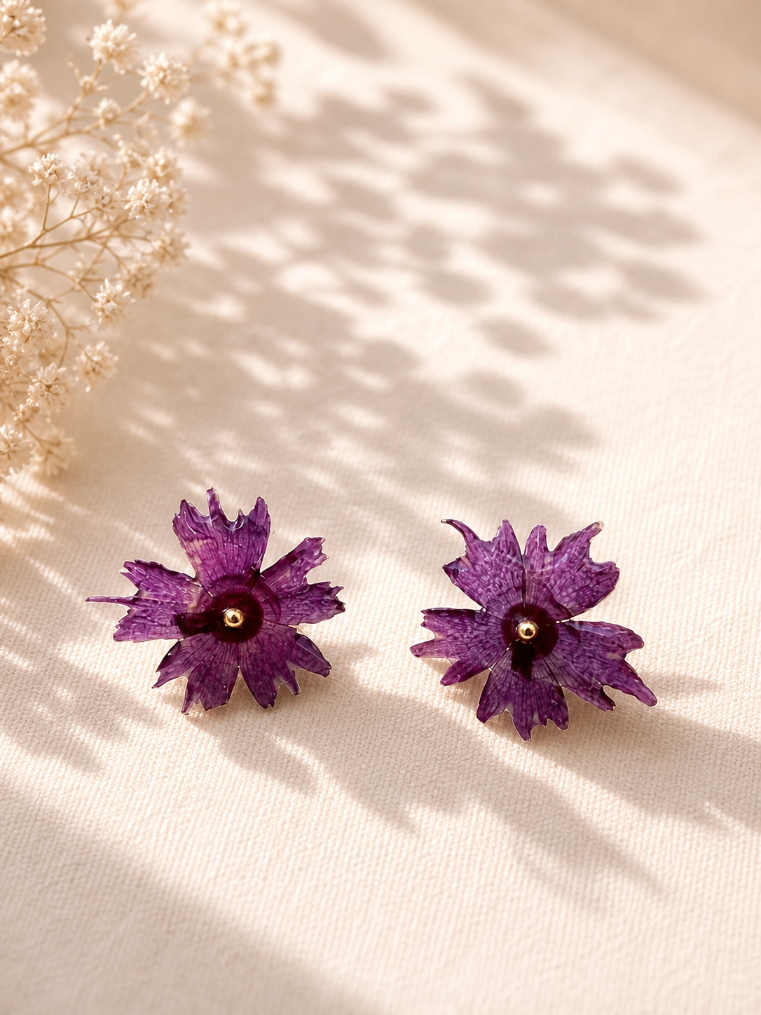 Close up of real flower resin stud earrings – whole purple bloom encased in clear UV resin, gold butterfly back, handmade in Lancashire UK