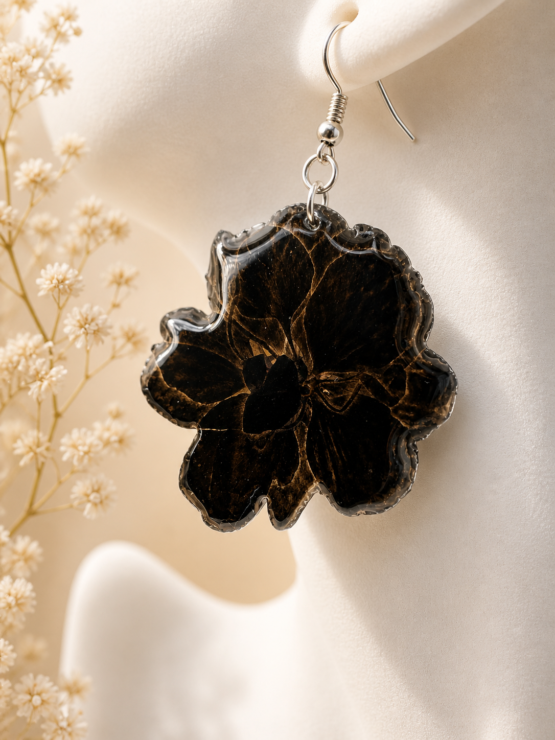 Black and gold resin flower drop earrings on mannequin with dried flowers in background, handmade in Lancashire UK