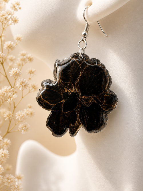 Black and gold resin flower drop earrings on mannequin with dried flowers in background, handmade in Lancashire UK