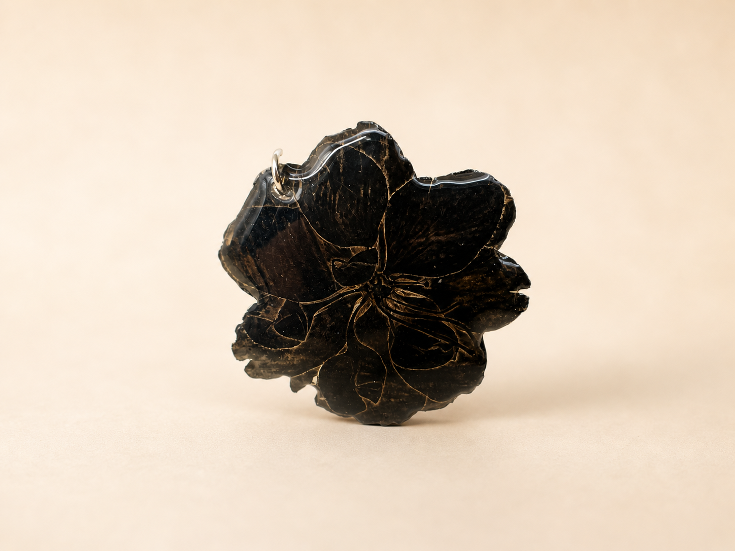 Close up of black resin flower pendant with gold vein detail, handmade resin earring by Held Forever Studio