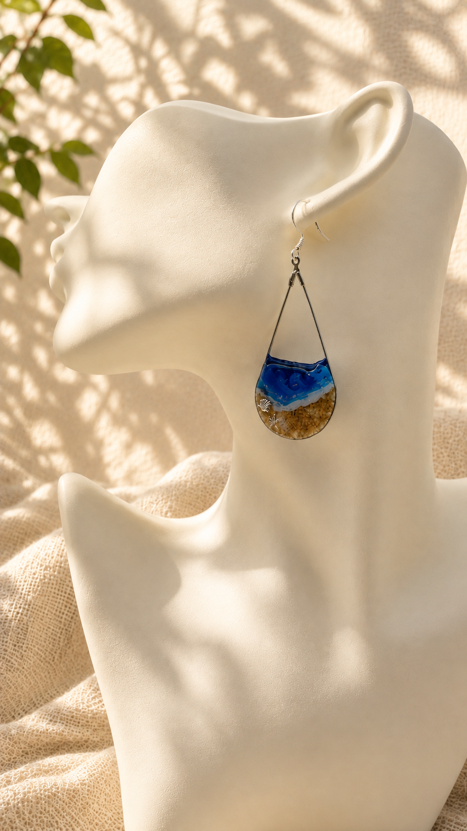 Pair of ocean wave resin drop earrings displayed on a gold stand, handmade in Lancashire UK