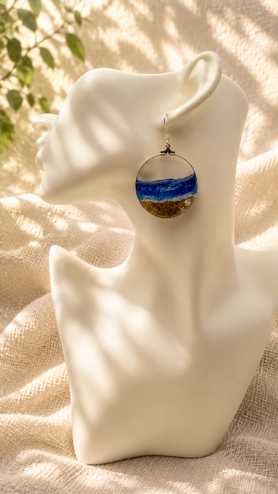 Ocean wave resin hoop earring worn on a display bust, showing the open circle wire frame and sand-textured base, handmade in Lancashire UK