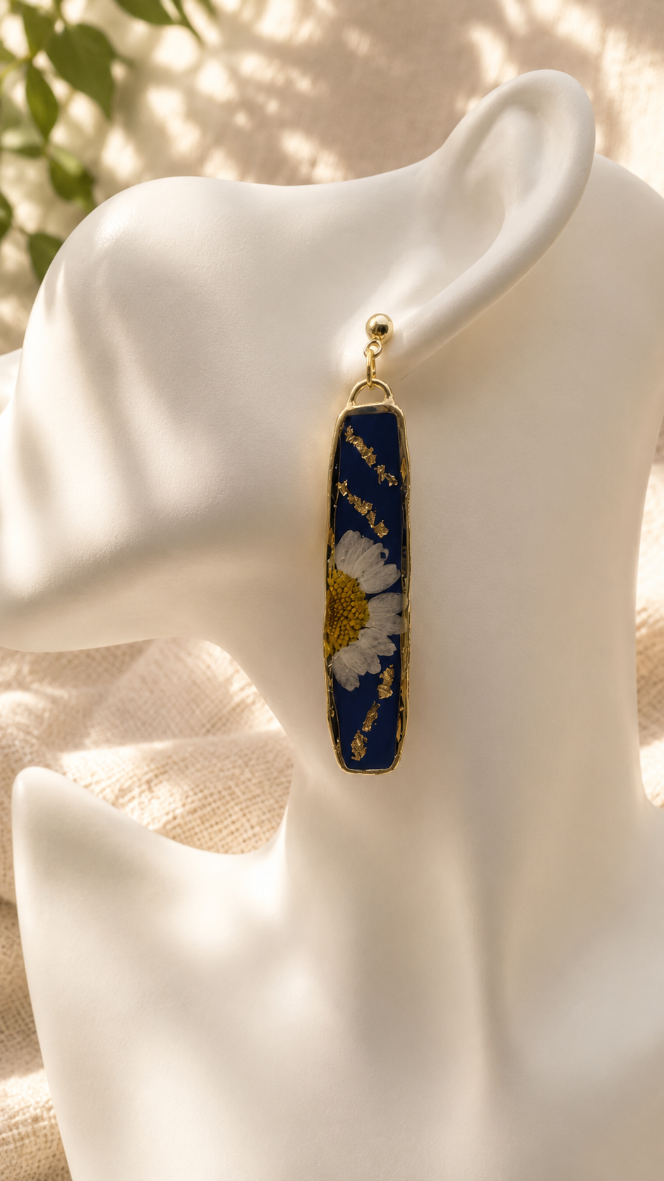 Close up of navy resin bar earring showing real pressed daisy and gold leaf detail, handmade by Held Forever Studio