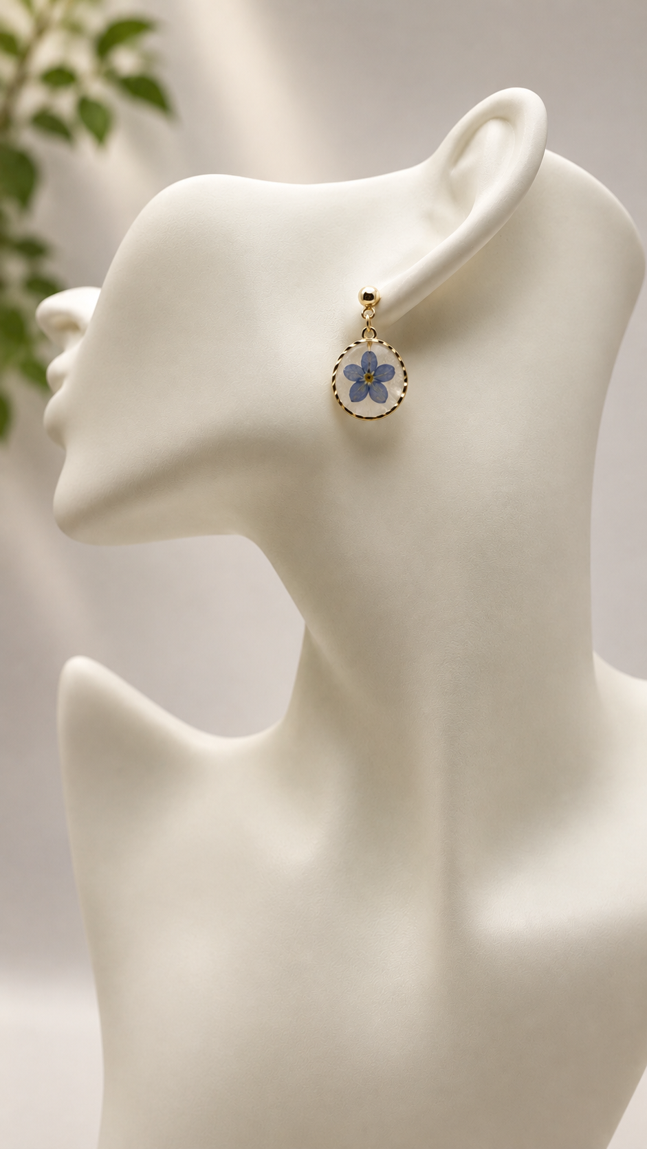 Close-up of a pressed forget-me-not resin disc earring worn, 24k gold-plated stud and bezel