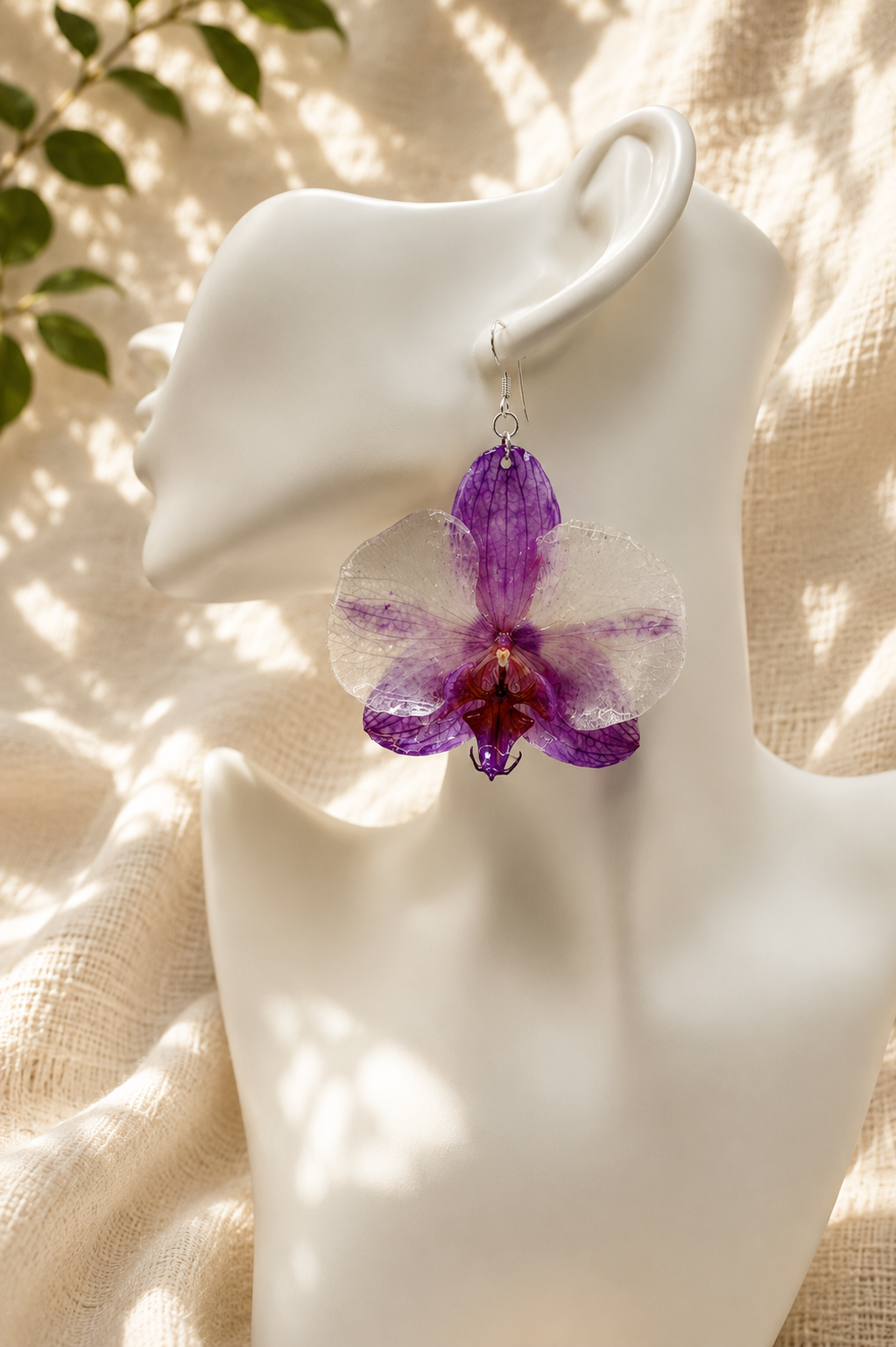 Pair of purple orchid resin drop earrings displayed on a stand, real preserved orchid blooms in clear resin, handmade in Lancashire UK