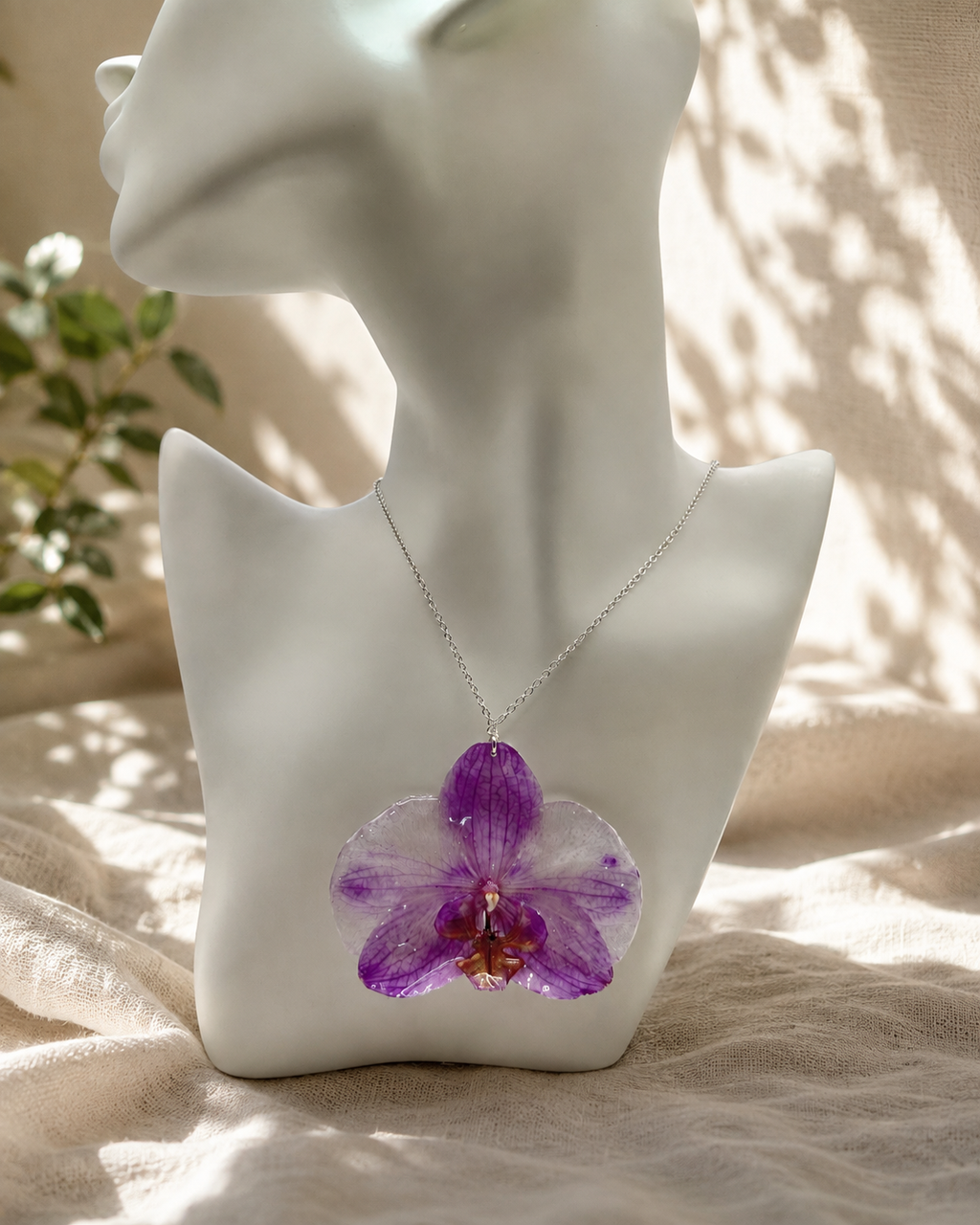 Purple orchid resin pendant necklace displayed on a stand, real preserved orchid bloom in clear resin, handmade in Lancashire UK