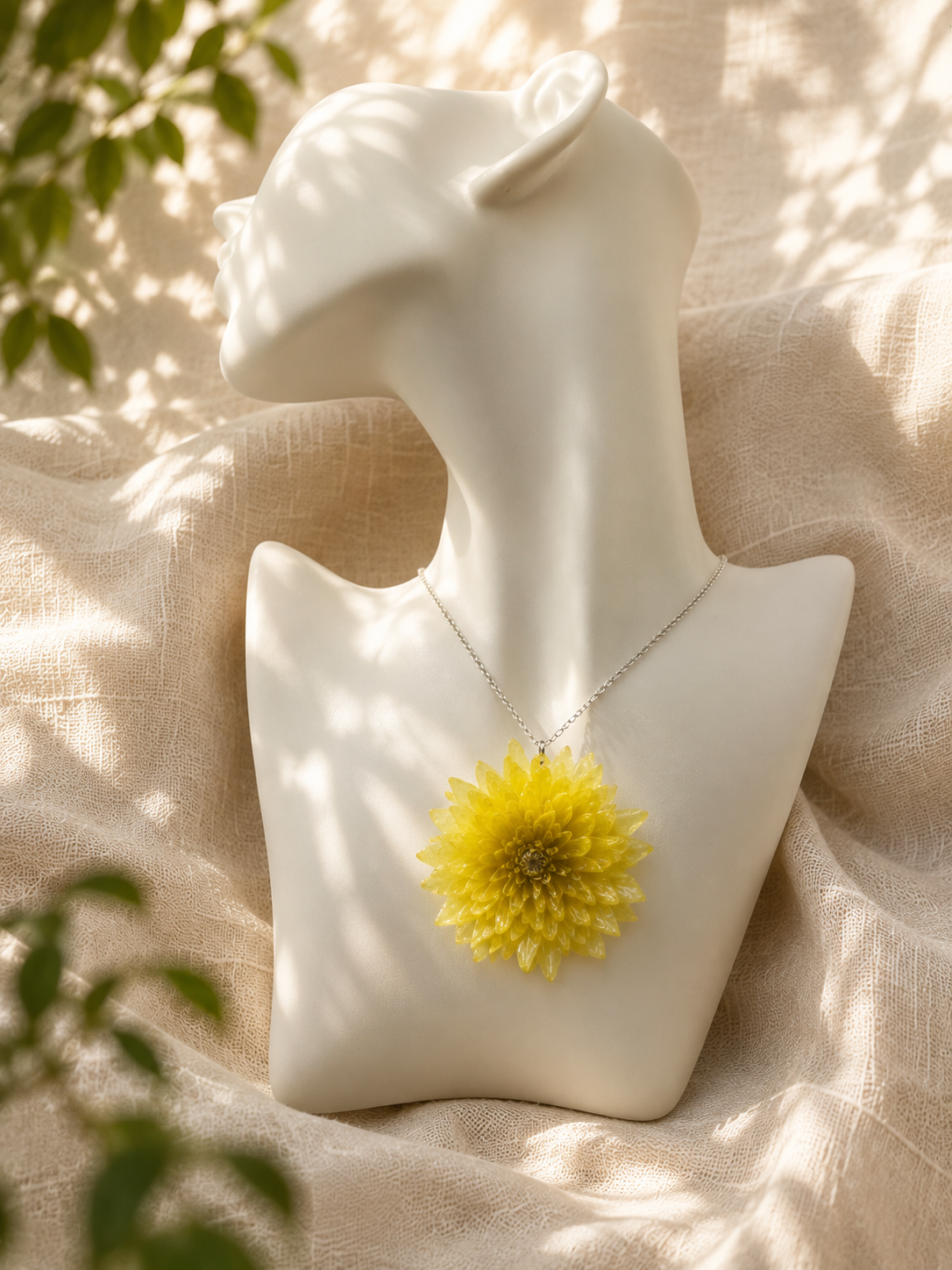 Yellow chrysanthemum resin pendant necklace displayed on a mannequin bust, handmade by Held Forever Studio