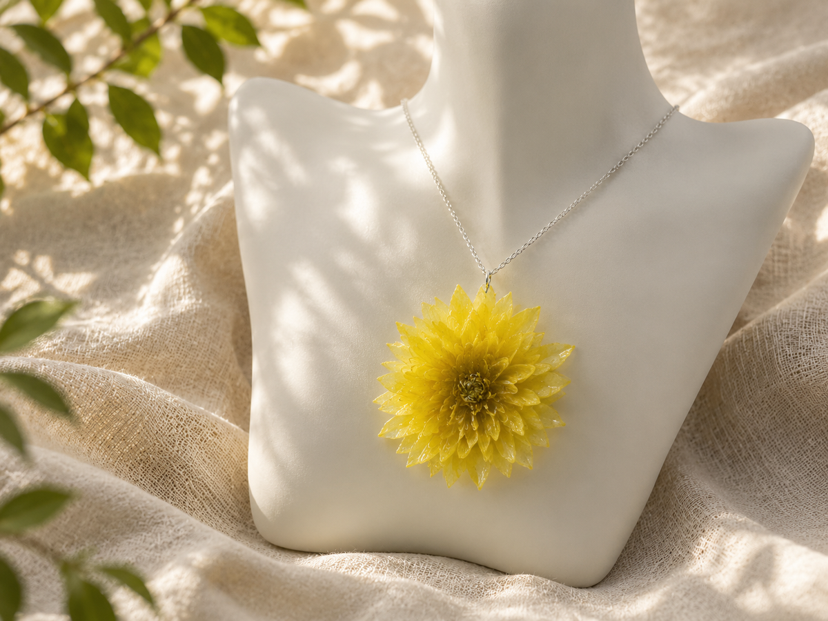 Close up of yellow chrysanthemum resin pendant on a stand showing the dimensional preserved petals, handmade in Lancashire UK