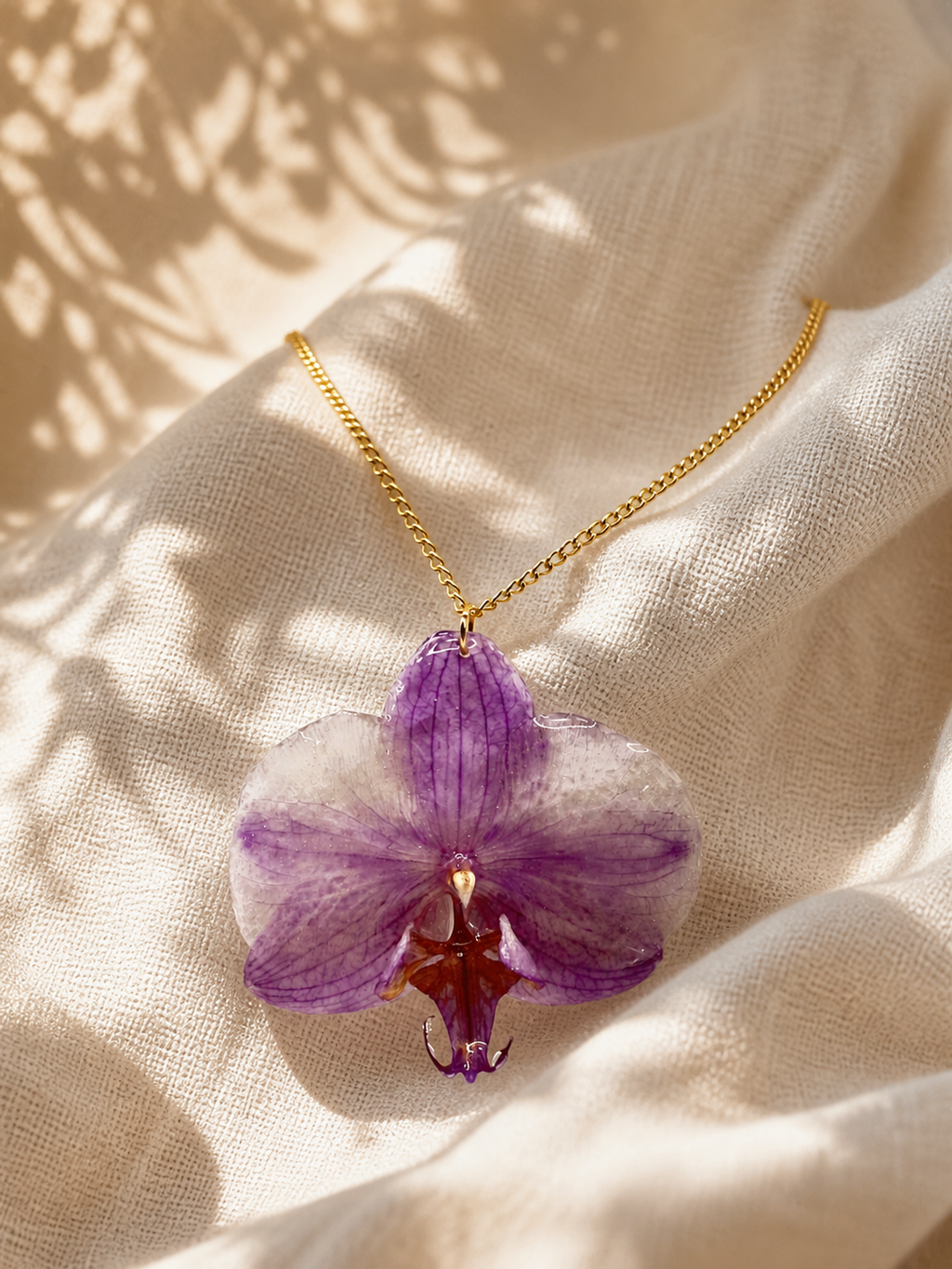 Purple orchid resin pendant necklace displayed on a bust stand, handmade in Lancashire UK