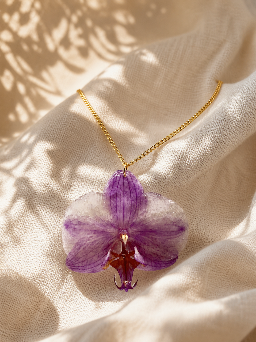 Purple orchid resin pendant necklace displayed on a bust stand, handmade in Lancashire UK