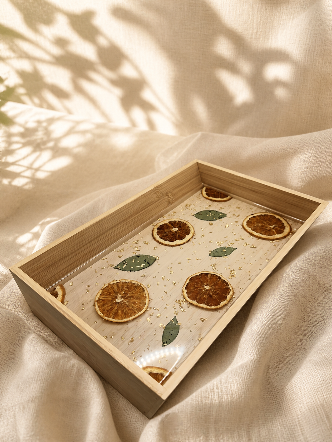 Angled view of the citrus resin tray showing dried orange slices and leaves set in resin, handmade by Held Forever Studio