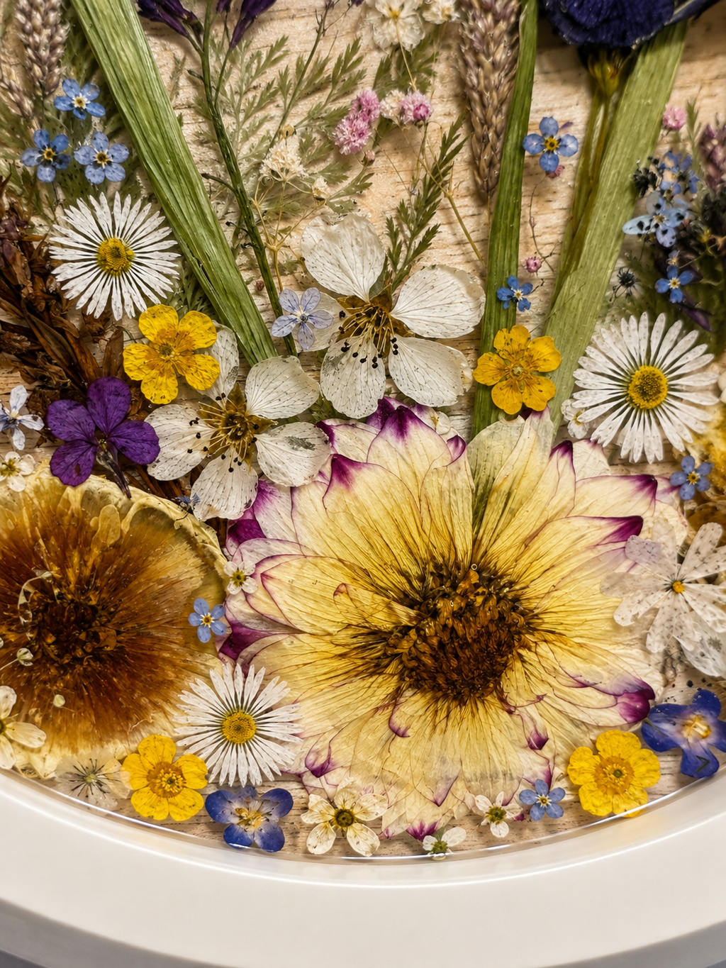 Close up of the round wildflower resin tray showing pressed grasses and a golden buttercup, handmade in Lancashire UK