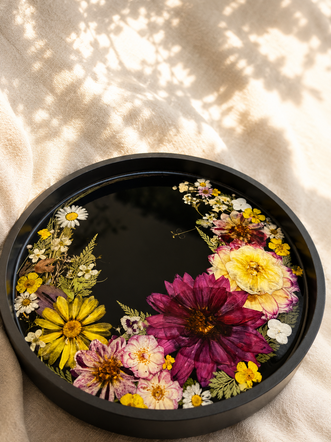 Top view of the black pressed wildflower resin tray on natural linen, handmade by Held Forever Studio