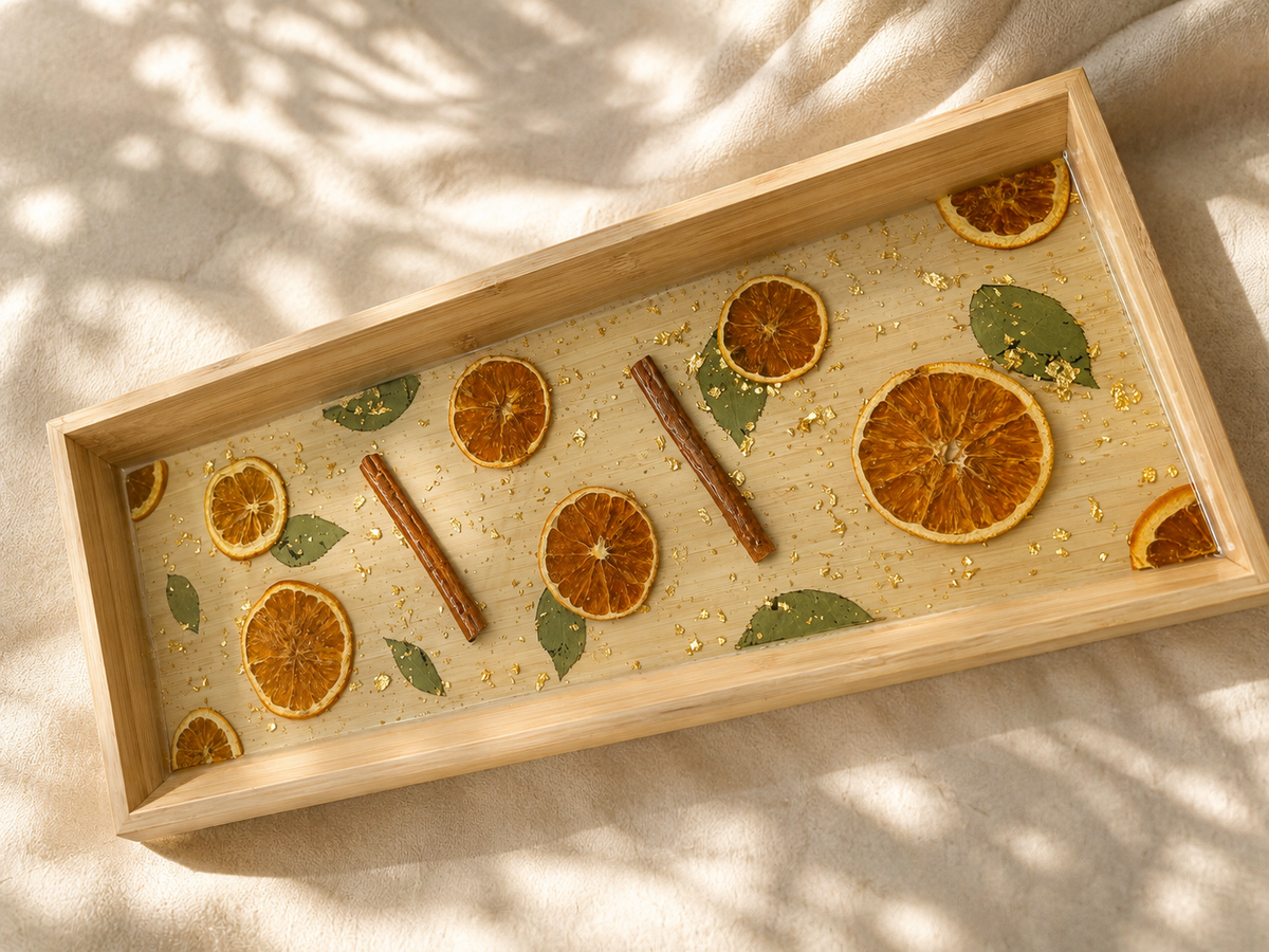 Detail of the dried orange slices, cinnamon sticks and gold flake set in resin in the long tray, handmade by Held Forever Studio