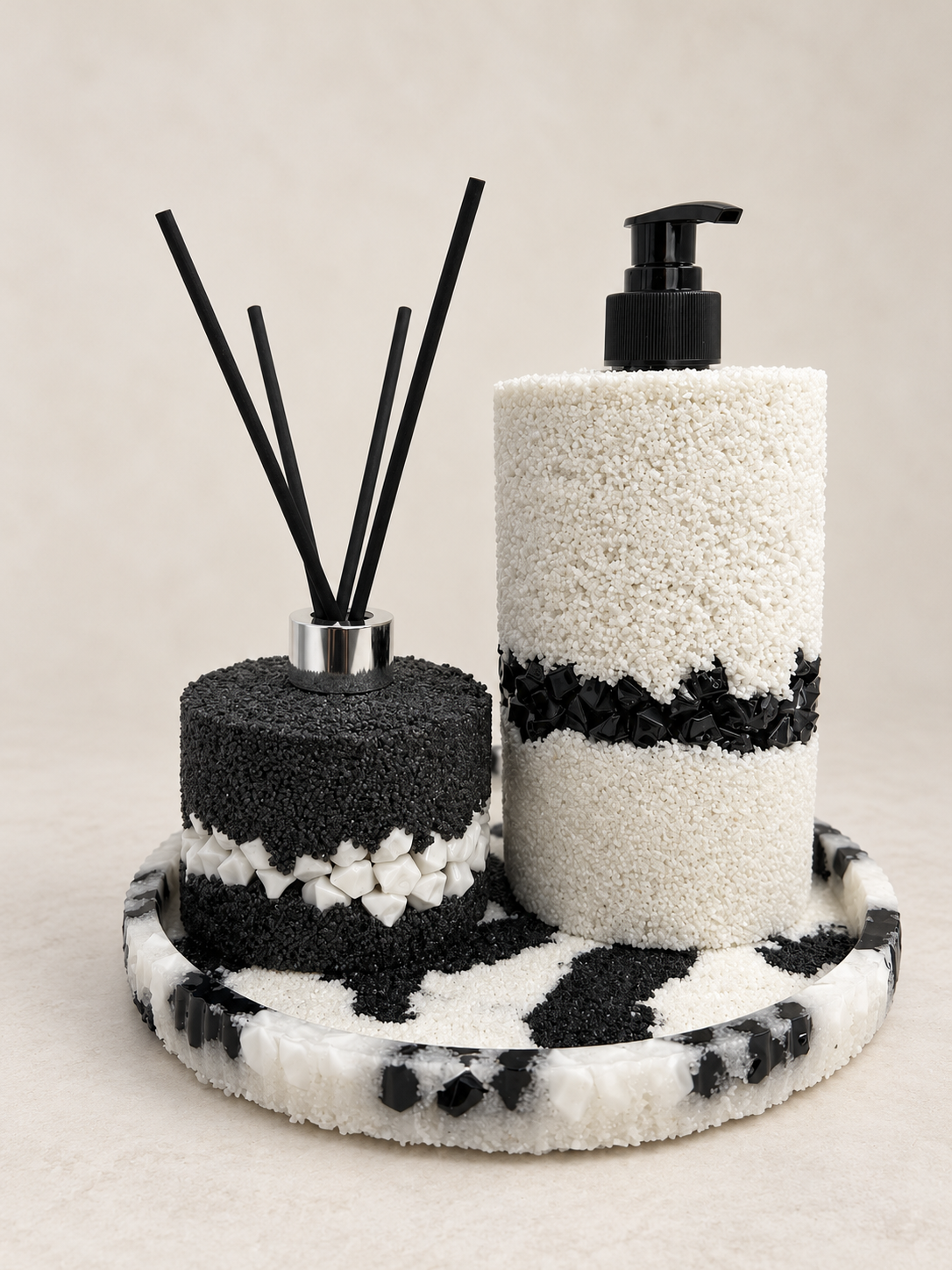 Black-and-white soap dispenser and diffuser bottle on a matching stone-and-sand tray, hand-decorated in Lancashire UK by Held Forever Studio; reeds shown for styling only